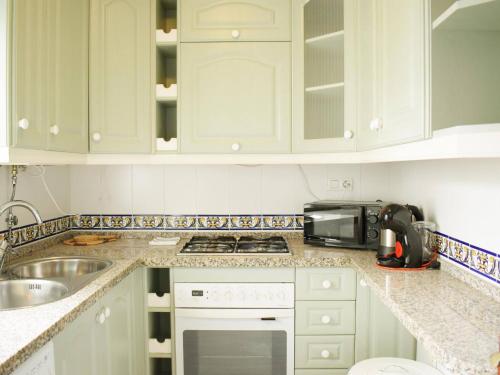 a kitchen with white cabinets and a sink and a microwave at Magnífico ático frente al mar en Ricón de la Victoria in Rincón de la Victoria