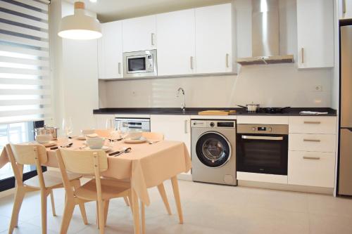 cocina con mesa con sillas y lavadora en Amalia's Home: Luminoso apartamento muy cerca de la playa, en Málaga