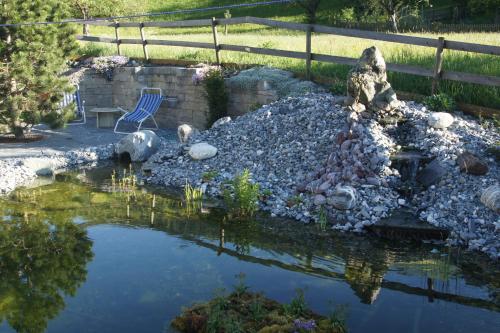 un estanque en un jardín con una silla en Beat & Ursula's Guest House en Jenaz