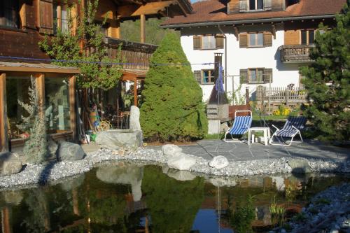 un jardín con sillas y un estanque frente a una casa en Beat & Ursula's Guest House en Jenaz