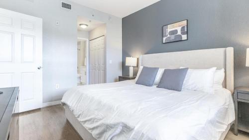 um quarto com uma grande cama branca com almofadas azuis em Landing - Modern Apartment with Amazing Amenities (ID8478X96) em Plantation