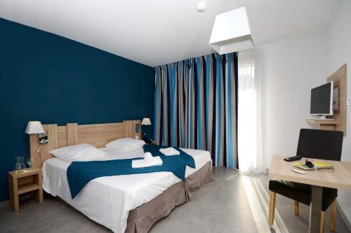una camera d'albergo con letto e parete blu di Appart'Hotel Prestige Odalys Nakâra a Cap d'Agde