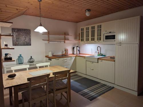 a kitchen with white cabinets and a wooden table at Vila Art Tatranská Lomnica in Vysoke Tatry - Tatranska Lomnica.