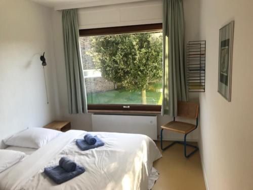 um quarto com 2 camas, uma janela e uma cadeira em Holiday Home Hoge Blekker em Koksijde