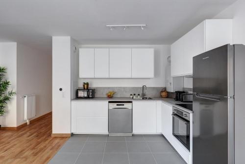 a kitchen with white cabinets and a stainless steel refrigerator at 340 Suite Emile - Superb apartment in Clichy