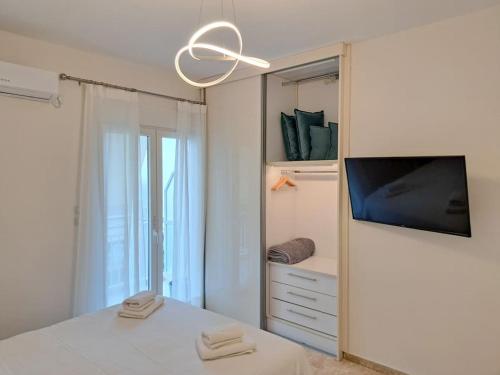 a white bedroom with a tv and a mirror at Luxury Suite Patras (2) in Patra