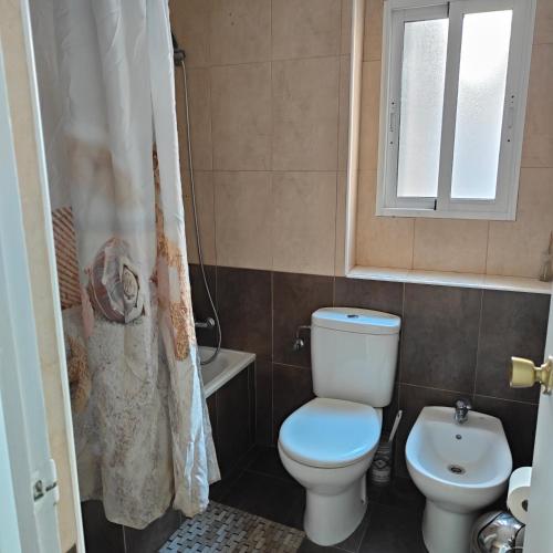 a bathroom with a toilet and a sink and a window at Relaxed Space in the beach in Puerto de Sagunto