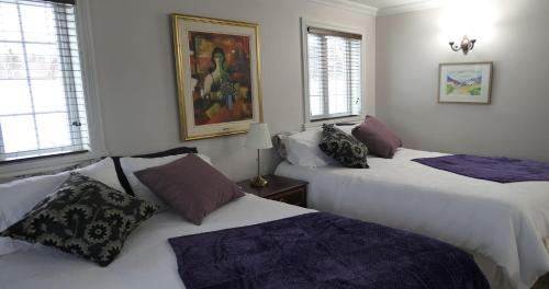 a bedroom with two beds and a painting on the wall at Auberge La Daïna in Baie-Saint-Paul