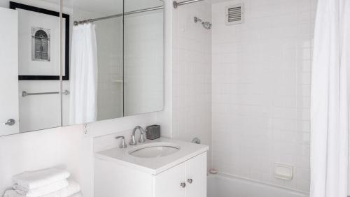 La salle de bains blanche est pourvue d'un lavabo et d'un miroir. dans l'établissement Landing - Modern Apartment with Amazing Amenities (ID5067X83), à New York