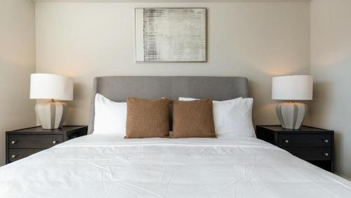 una camera con un letto bianco e 2 lampade di Landing - Modern Apartment with Amazing Amenities (ID8251X95) a Wake Forest