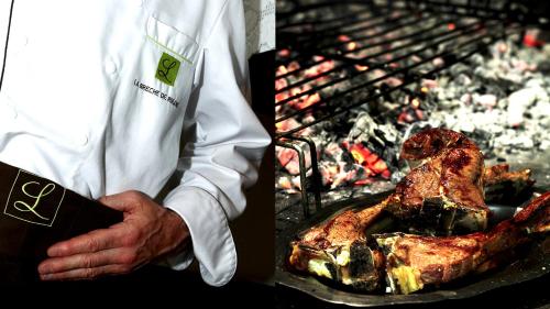 ジェドルにあるロジ オテル ラ ブレシェ ドゥ ローランドの肉焼きの前に立つ男