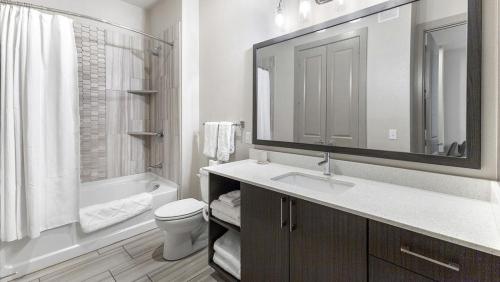 een badkamer met een wastafel, een toilet en een spiegel bij Landing - Modern Apartment with Amazing Amenities (ID5020X49) in Plano