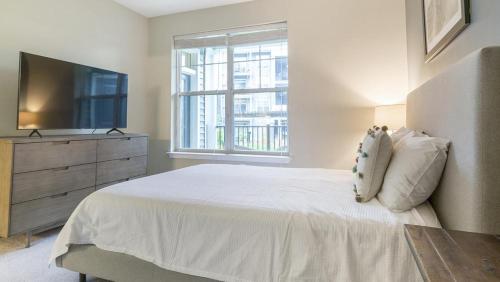 een witte slaapkamer met een bed en een televisie bij Landing - Modern Apartment with Amazing Amenities (ID2905X13) 