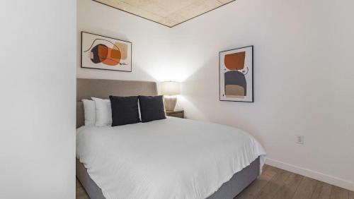 um quarto com uma cama branca e duas fotografias na parede em Landing - Modern Apartment with Amazing Amenities (ID1187X358) em Portland