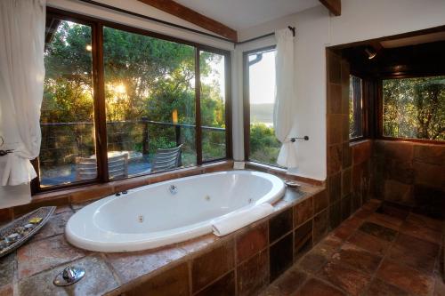 a large bath tub in a bathroom with a window at Elephant Hide of Knysna Guest Lodge in Knysna