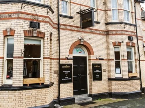 um edifício de tijolos com uma porta preta numa rua em The Keyberry Hotel em Newton Abbot