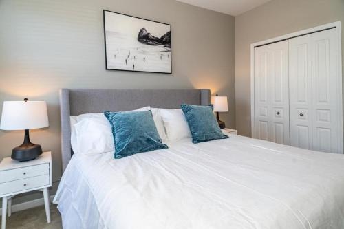 a bedroom with a large white bed with blue pillows at Landing - Modern Apartment with Amazing Amenities (ID4378) in Auburn Hills