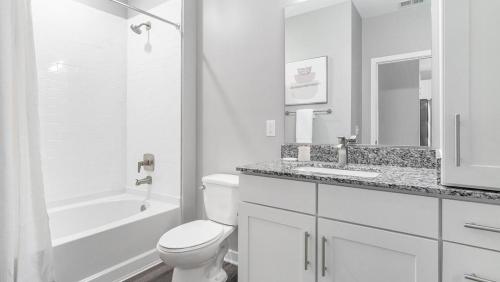 a white bathroom with a toilet and a tub and a sink at Landing - Modern Apartment with Amazing Amenities (ID9798X32) in Chapel Hill