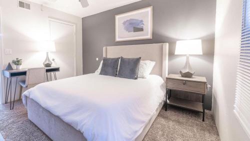 1 dormitorio con 1 cama blanca con 2 mesas y 2 lámparas en Landing - Modern Apartment with Amazing Amenities (ID7250X84) en Albuquerque