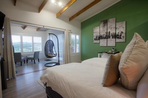 a bedroom with green walls and a bed and a table at Elephant Hide of Knysna Guest Lodge in Knysna