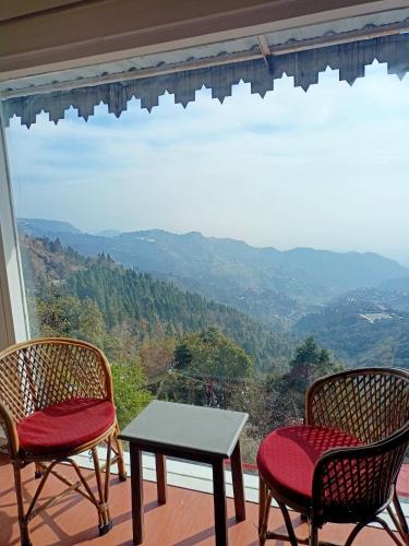 two chairs and a table on a balcony with a view at Beechwood Holiday Apartments in Mussoorie