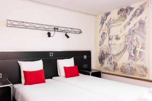 two beds in a room with two red pillows at Backstage Hotel Amsterdam in Amsterdam