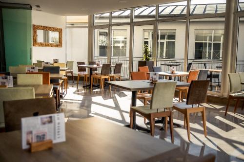 an empty restaurant with tables and chairs and windows at Barbara Piran Beach Hotel in Piran