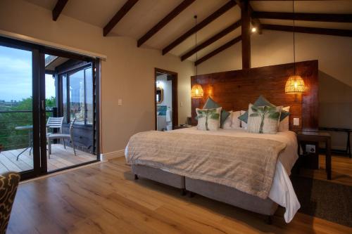 a bedroom with a large bed and a balcony at Elephant Hide of Knysna Guest Lodge in Knysna