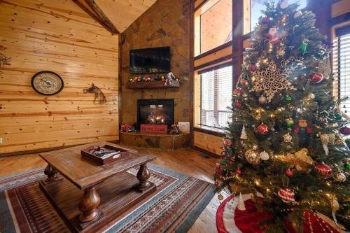 a christmas tree in a living room with a fireplace at Iron Horse Lodge sleeps 18, Games, Fire Pit, Hot Tub, EV, more in Broken Bow