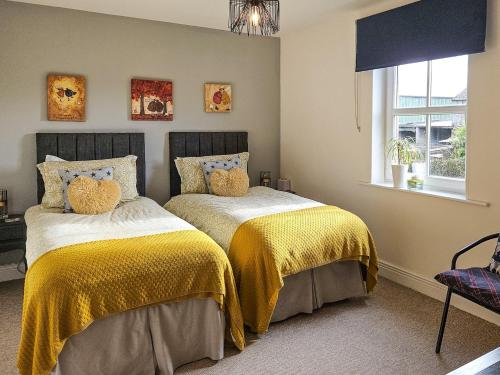 two beds in a bedroom with yellow blankets at 4 Bed in Hayton SZ119 in Hayton