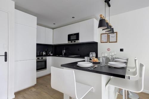 een keuken met witte kasten en een zwarte tafel en stoelen bij 322 Suite Fes - Superb apartment in Suresnes