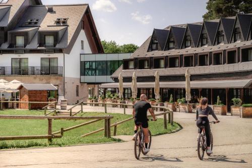 un hombre y una mujer montando bicicletas delante de un edificio en Hotel Arena Maribor en Maribor