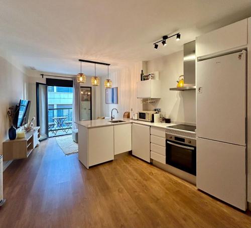 a kitchen with white appliances and wooden floors at Sol Mediterráneo Palm City in Elche