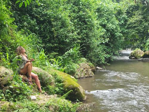 a woman sitting on a rock next to a river at Holiday cottage by the river, Arusha in Arusha