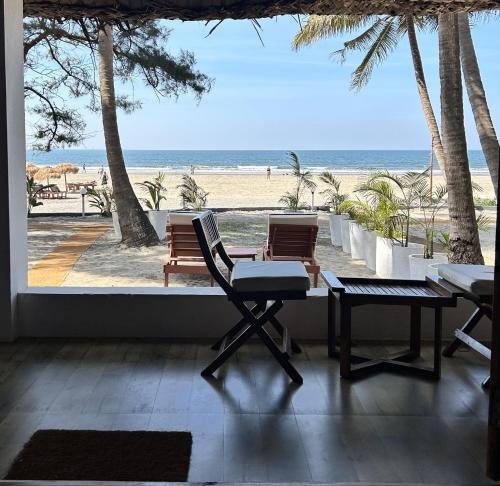 Mamagoa Beach Resort في ماندريم: غرفة مطلة على شاطئ مع كرسيين