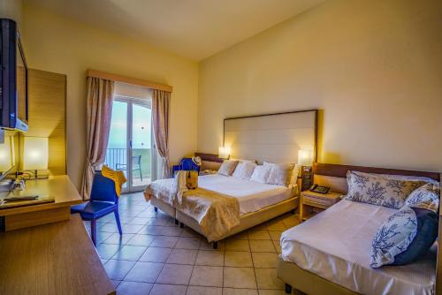una habitación de hotel con 2 camas y una silla en GH Avalon Sikani, en Gioiosa Marea