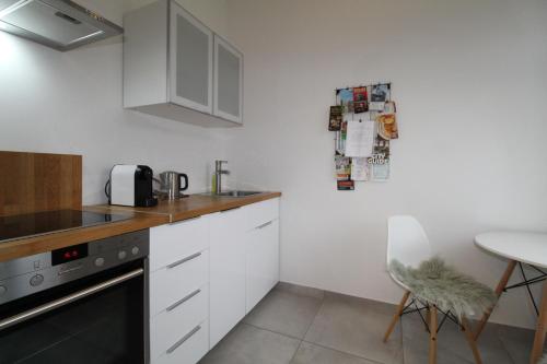a kitchen with white cabinets and a table with a chair at Zentrales hochwertiges Gründerzeit-Apartment Thomasius in Leipzig