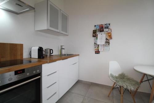 una cocina con armarios blancos y una mesa con una silla en Zentrales hochwertiges Gründerzeit-Apartment Thomasius, en Leipzig