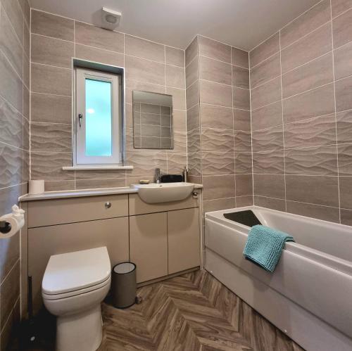 La salle de bains est pourvue de toilettes, d'un lavabo et d'une baignoire. dans l'établissement Shoreside Villa - immaculate waterfront property in Skelmorlie, à Skelmorlie