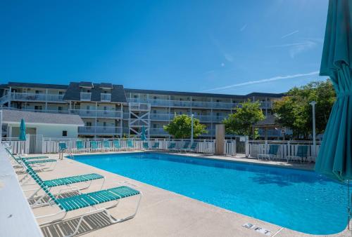 a swimming pool with lounge chairs and a building at Ocean Dunes 0903 in Kure Beach