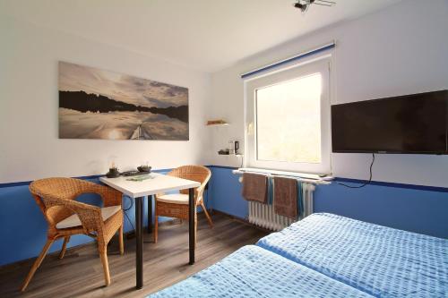 a room with a bed and a table and a tv at Toms Gästehaus in Schleiden