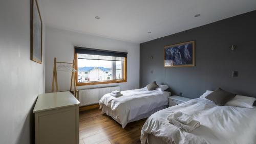 een slaapkamer met 2 bedden en een raam bij Hostel Belator Experience in Puerto Natales