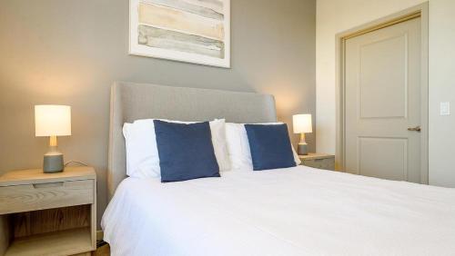 a bedroom with a white bed with blue pillows at Landing - Modern Apartment with Amazing Amenities (ID8201X09) in Orlando