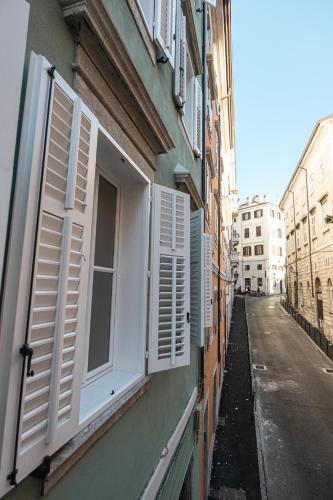 a building with white shuttered windows on a street at Hurban Apartments Venezian in Trieste