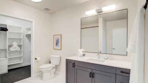 La salle de bains est pourvue de toilettes, d'un lavabo et d'un miroir. dans l'établissement Landing - Modern Apartment with Amazing Amenities (ID8310X07), à Salt Lake City