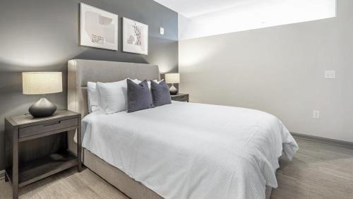 ein Schlafzimmer mit einem weißen Bett und einem Nachttisch mit einer Lampe in der Unterkunft Landing - Modern Apartment with Amazing Amenities (ID1208X248) in Charlotte