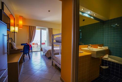 une salle de bain avec un lavabo, un lit et un miroir dans l'établissement GH Avalon Sikani, à Gioiosa Marea