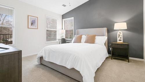 1 Schlafzimmer mit einem weißen Bett und 2 Fenstern in der Unterkunft Landing - Modern Apartment with Amazing Amenities (ID8245X00) in Winston-Salem