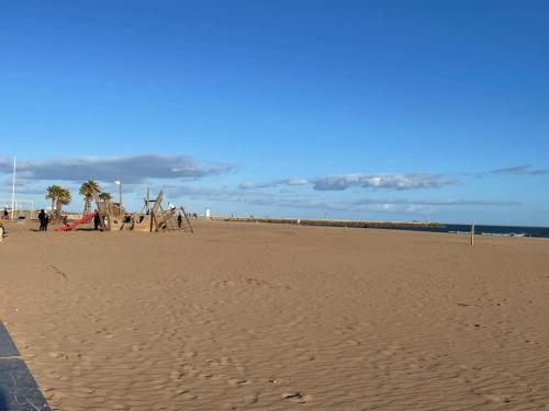 einen Sandstrand mit Palmen und einem Spielplatz in der Unterkunft Vos vacances à la mer in Valras-Plage