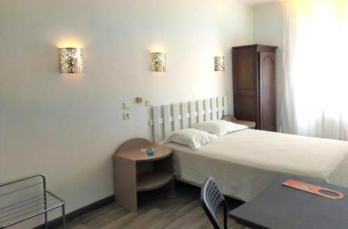 a hotel room with a bed and a table at Au Nouvel H&ocirc;tel in Toulon